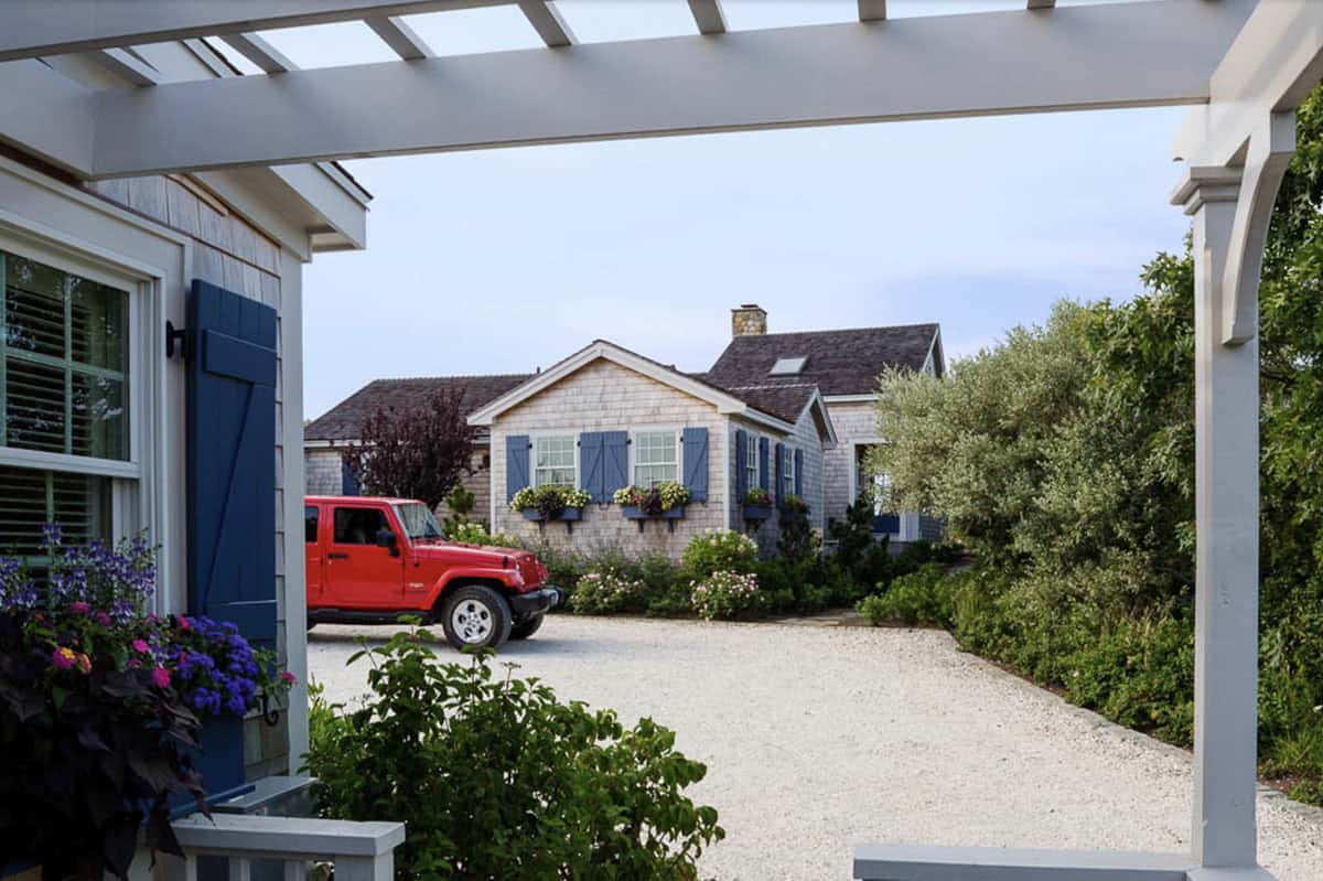 Cedar shingle beach cottage with blue shutters and window boxes framed by white pergola columns