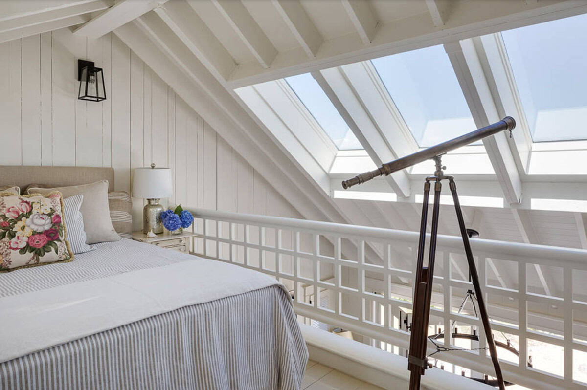 Loft bedroom with skylights, ticking stripe bedding, exposed beams, and vintage brass telescope