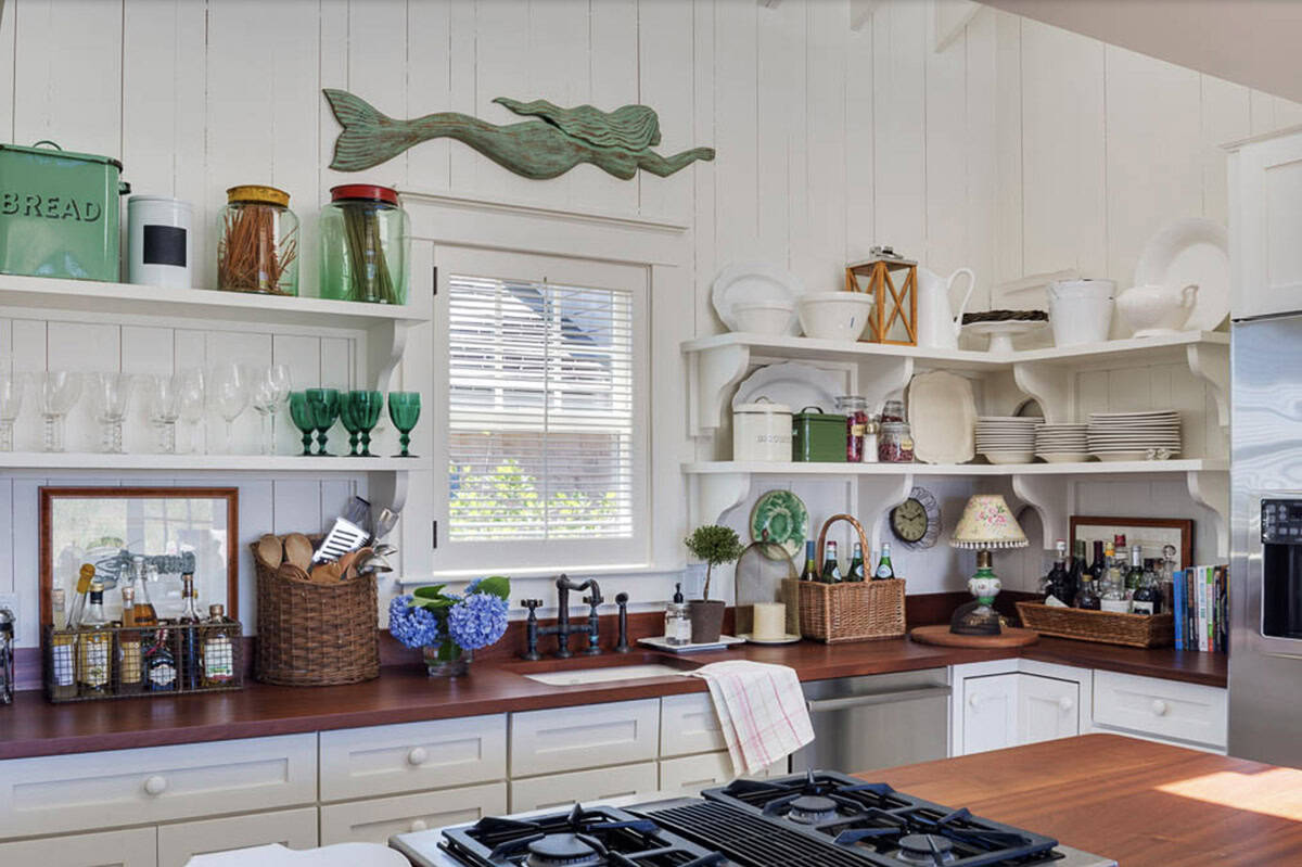 Cottage kitchen with open shelving, wood countertops, wooden mermaid wall art, and vintage collectibles