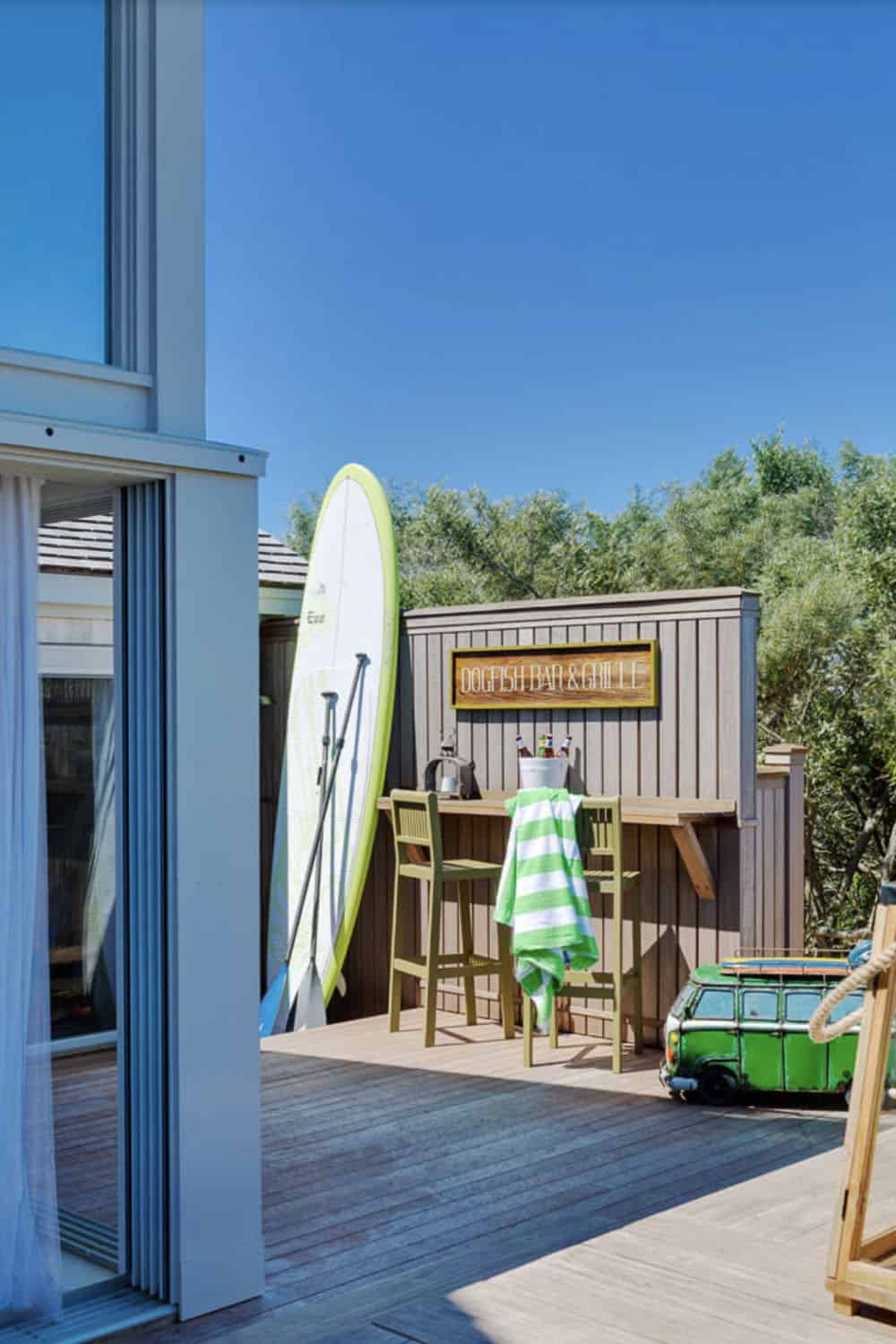 Beach house deck with surfboard, paddle, and Dogfish Bar and Grille outdoor bar setup