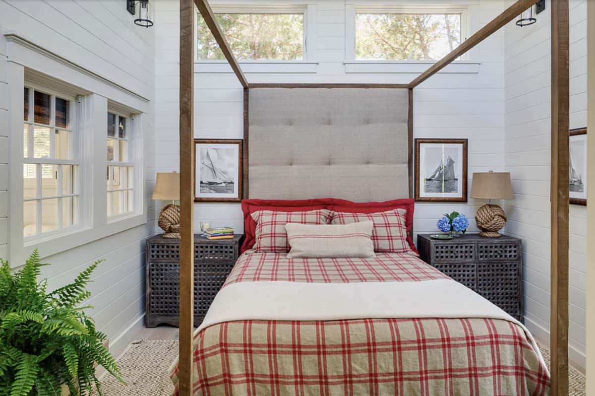 Cottage bedroom with wood four-poster bed, red plaid bedding, sailboat prints, and rope-knot nightstand lamps