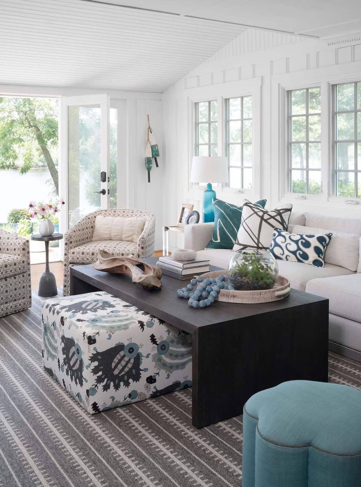 Living room detail with ikat ottoman, dark coffee table, teal accents, and layered coastal pillows