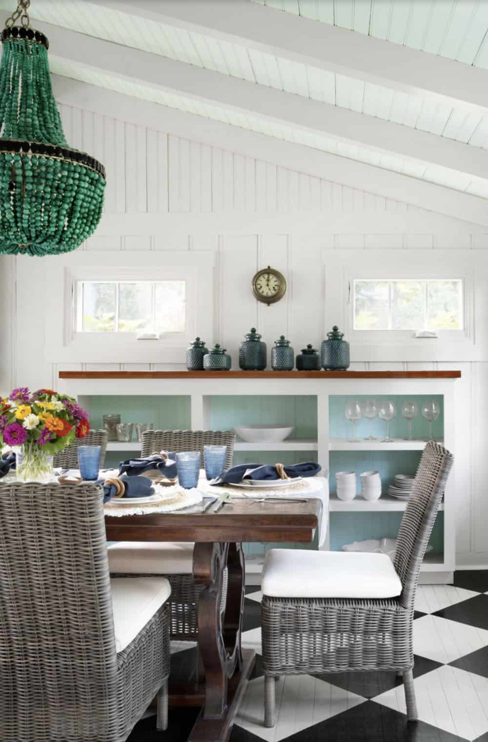 Dining room detail with green beaded chandelier, built-in shelving with teal accents, and wicker chairs