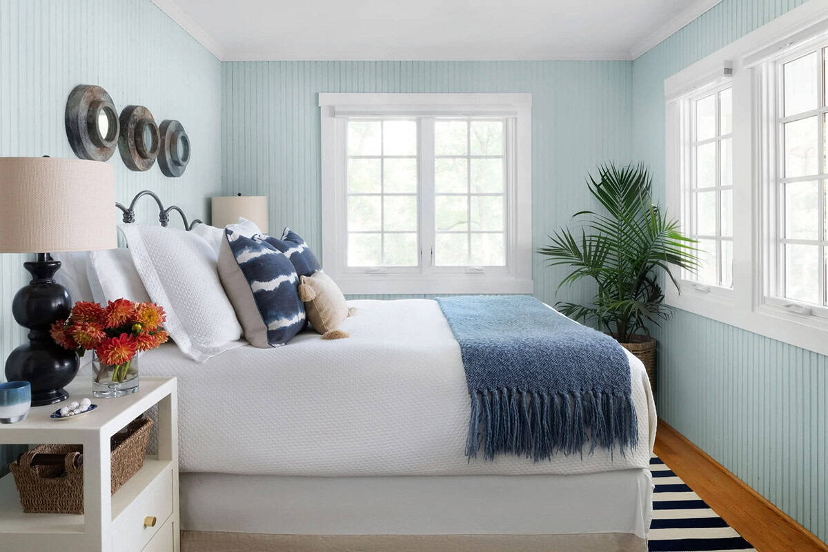 Coastal bedroom with pale blue beadboard walls, indigo shibori pillows, navy throw, and tropical palm plant