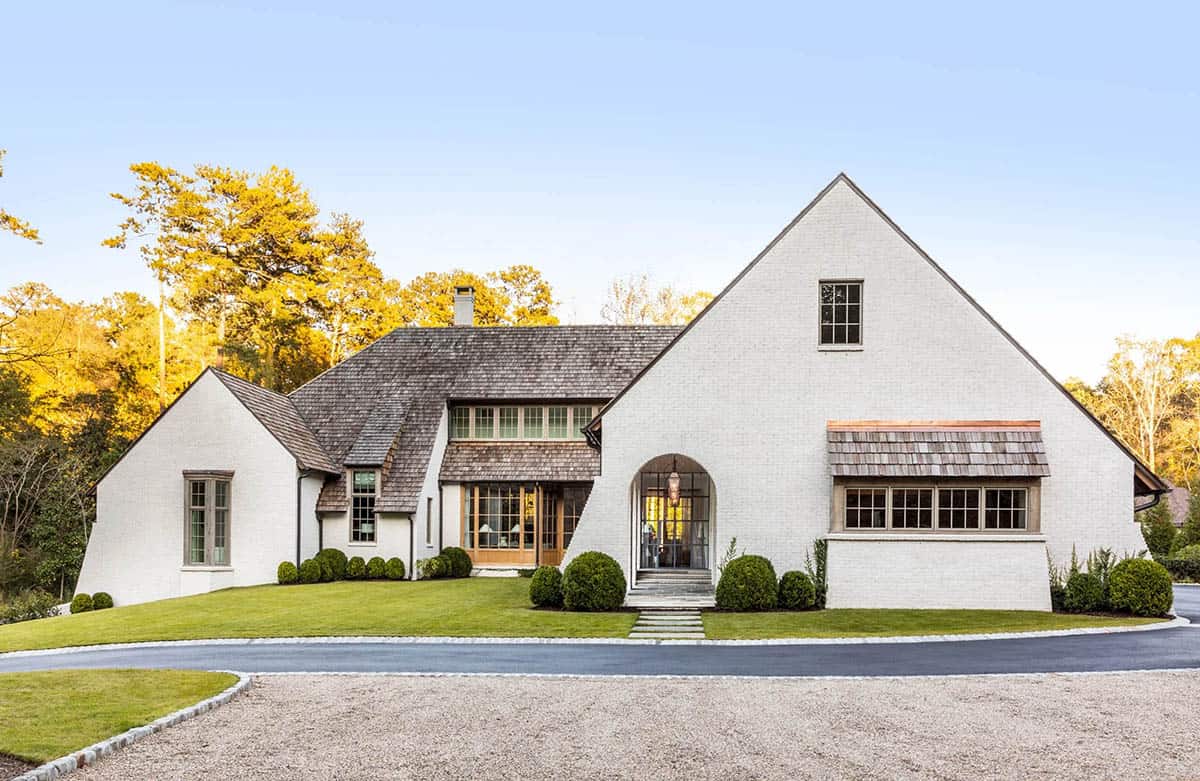 Belgian farmhouse inspired home exterior with white painted brick, steep gabled roofline, and arched entry