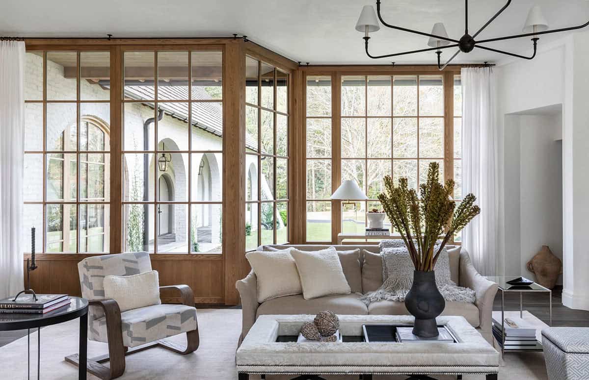Living room with floor-to-ceiling oak-framed windows, neutral sofa, and iron chandelier