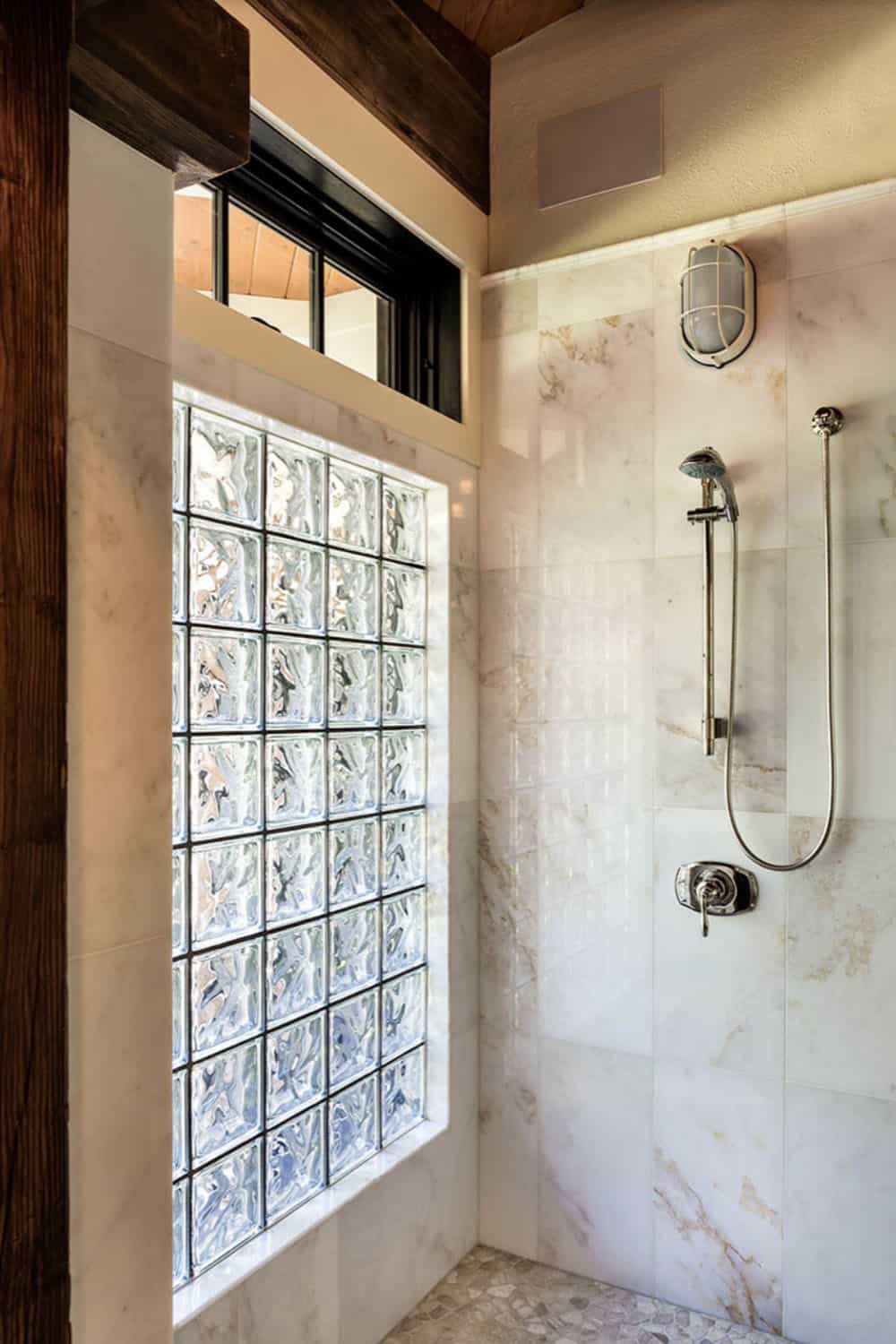 Main bathroom walk-in shower with glass block privacy window, marble tile surround, and chrome fixtures