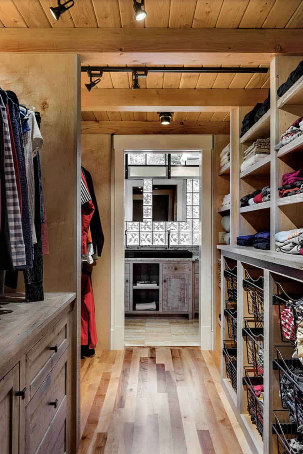 Walk-through master closet with pine ceiling, open shelving, wire baskets, and view through to bathroom vanity