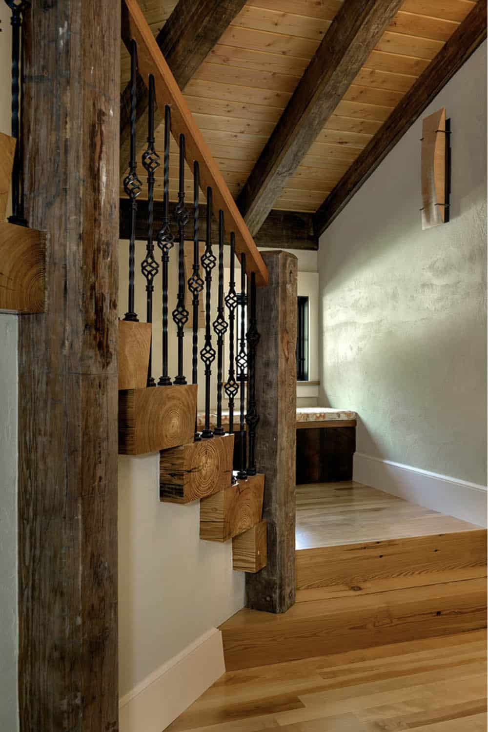 Staircase with chunky reclaimed timber treads, ornate wrought iron balusters, and knotty pine ceiling