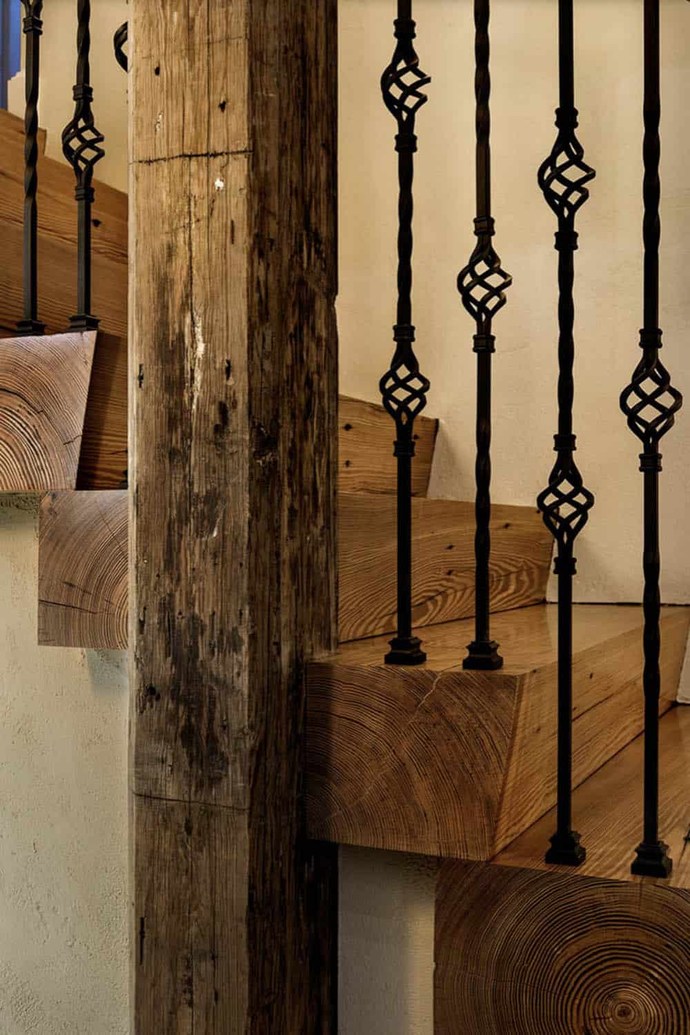 Close-up detail of chunky reclaimed timber stair treads with ornate wrought iron cage balusters