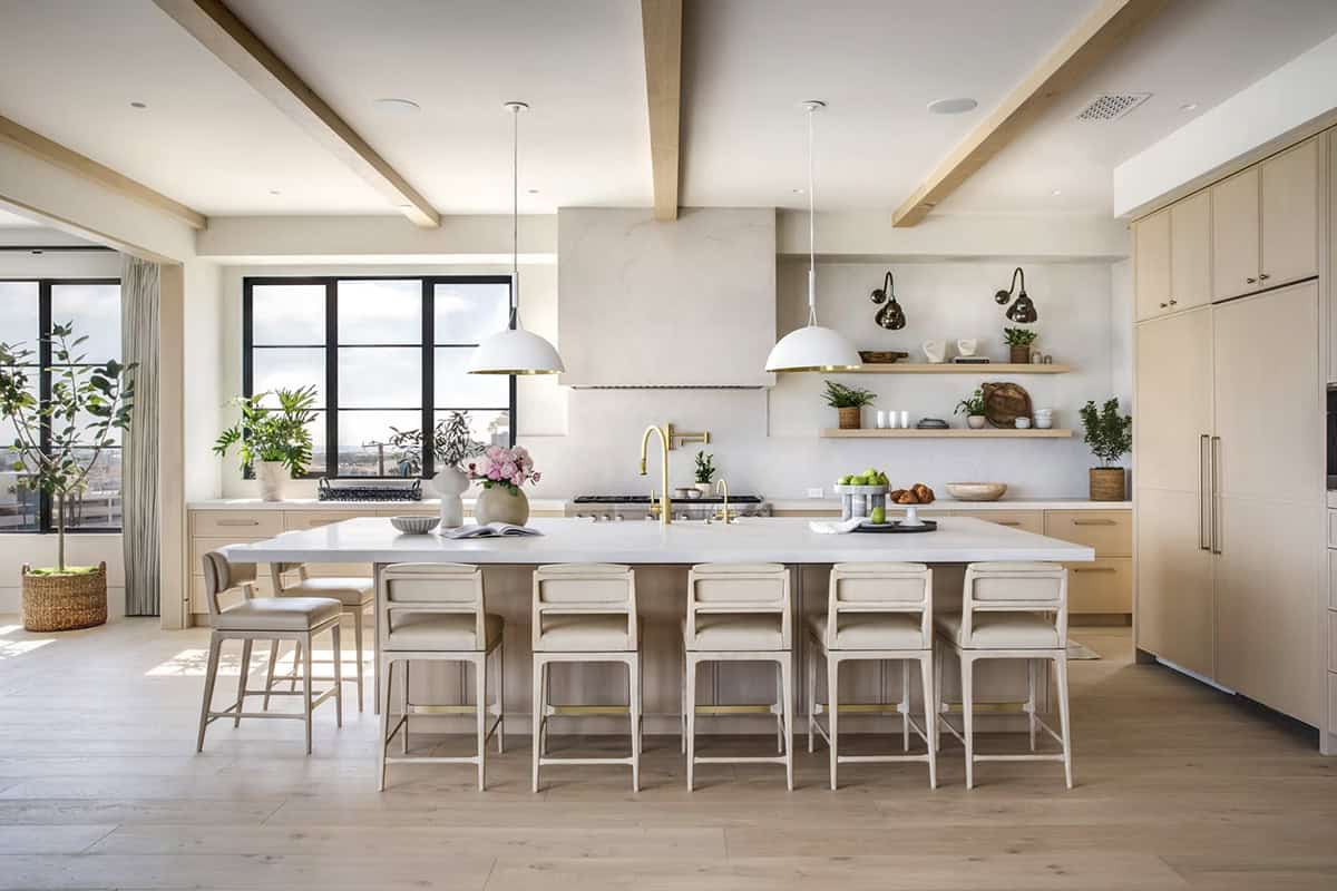 Large kitchen with oversized white island, dome pendant lights, brass fixtures, and light wood cabinetry