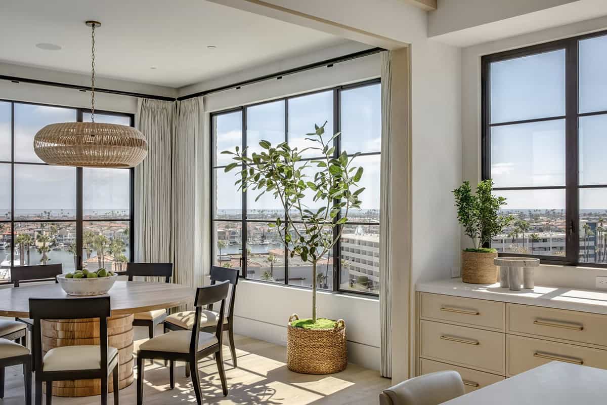 Dining nook with harbor views, woven pendant light, and fiddle-leaf fig in basket planter