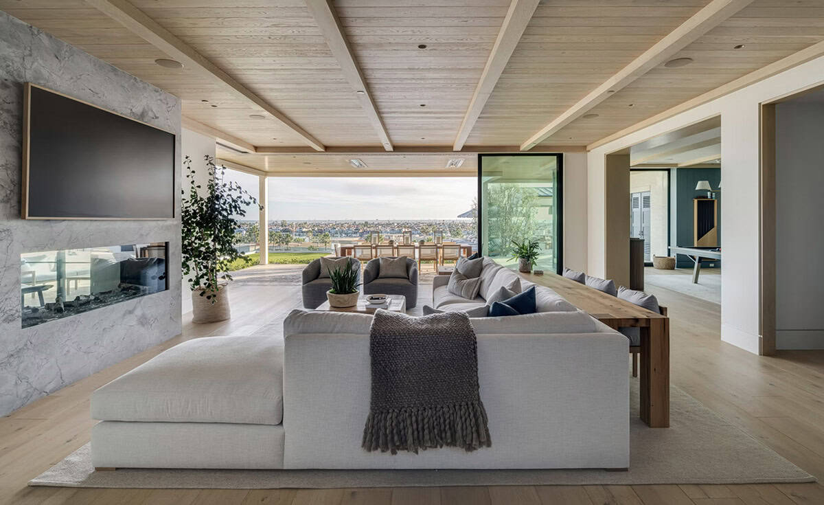 Living room with oversized sectional, marble fireplace surround, wood-plank ceiling, and ocean views