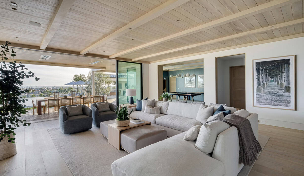 Casual living area with light sectional, wood-plank ceiling, and view to outdoor dining terrace