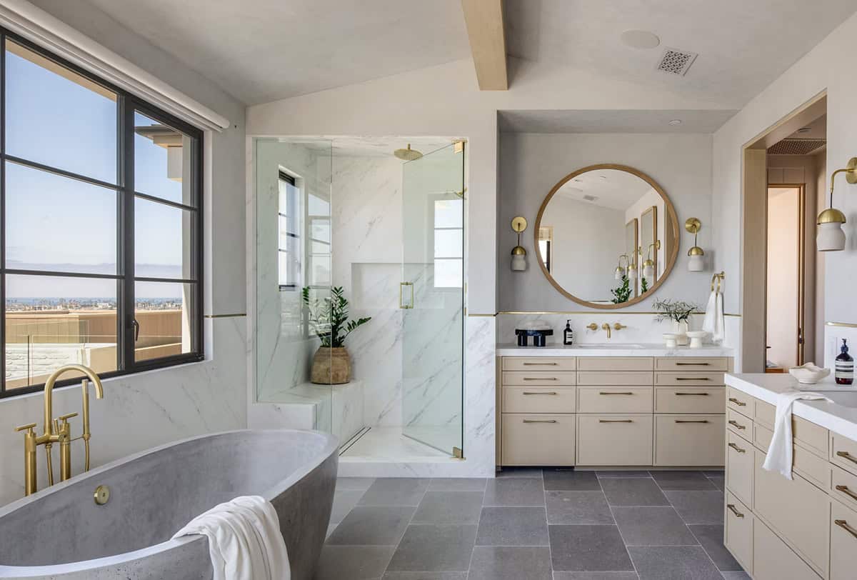 Primary bathroom with concrete soaking tub, glass-enclosed marble shower, and sand-toned double vanity with round wood mirror