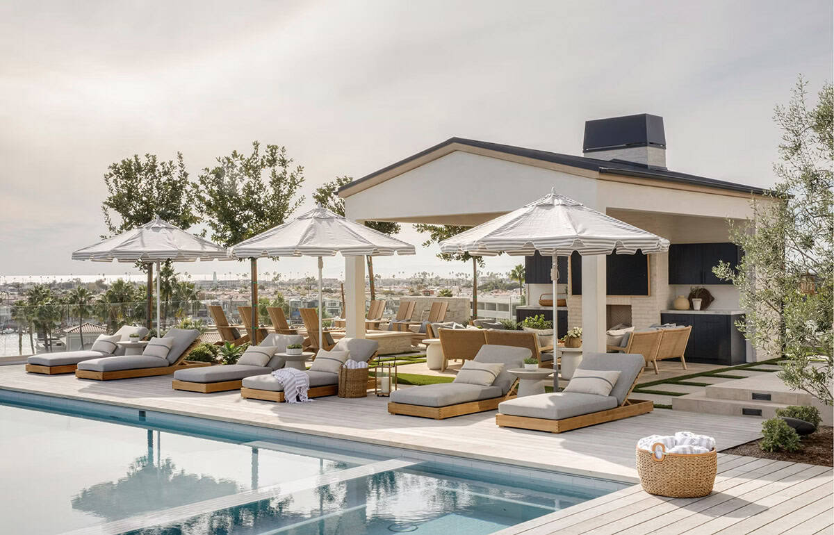 Pool deck with teak chaise lounges, striped cabana umbrellas, outdoor bar, and harbor views