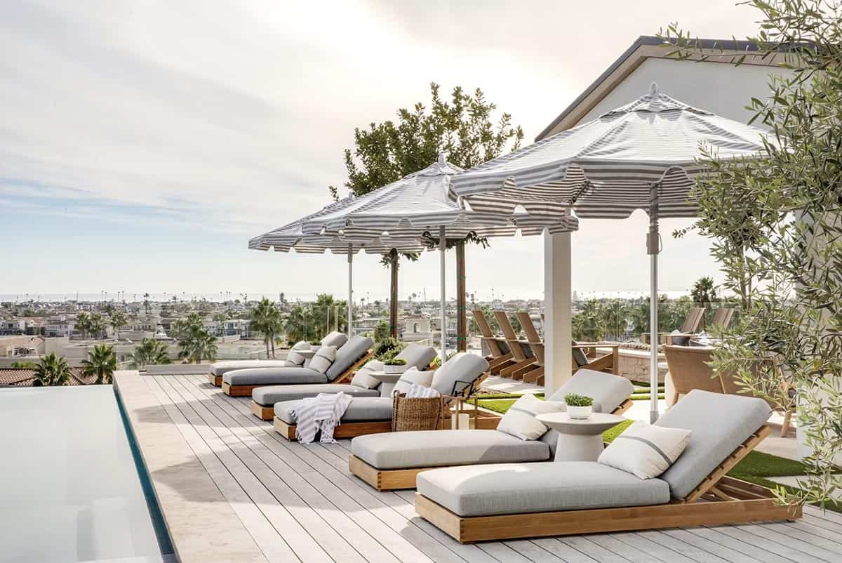 Poolside lounge chairs with striped scalloped umbrellas and panoramic coastal cityscape