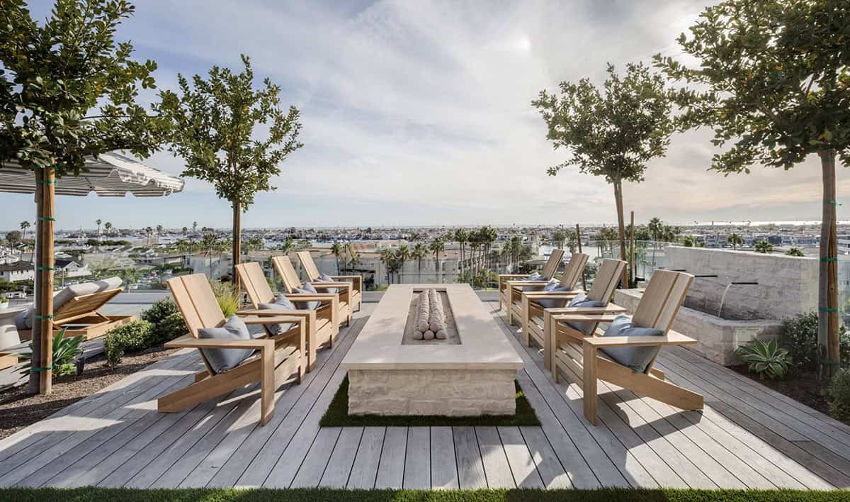 Rooftop fire pit terrace with teak Adirondack chairs, stone fire table, and 360-degree coastal views