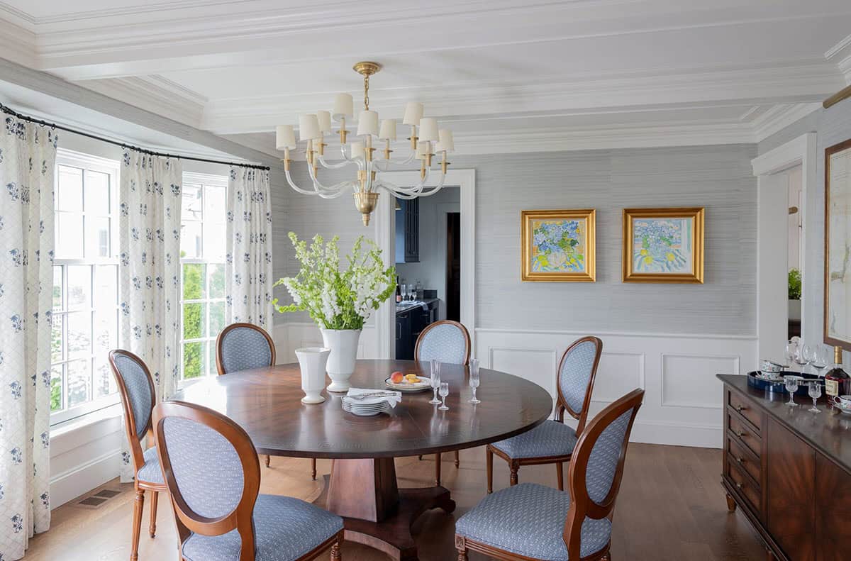 Formal dining room with grasscloth walls, round pedestal table and crystal chandelier