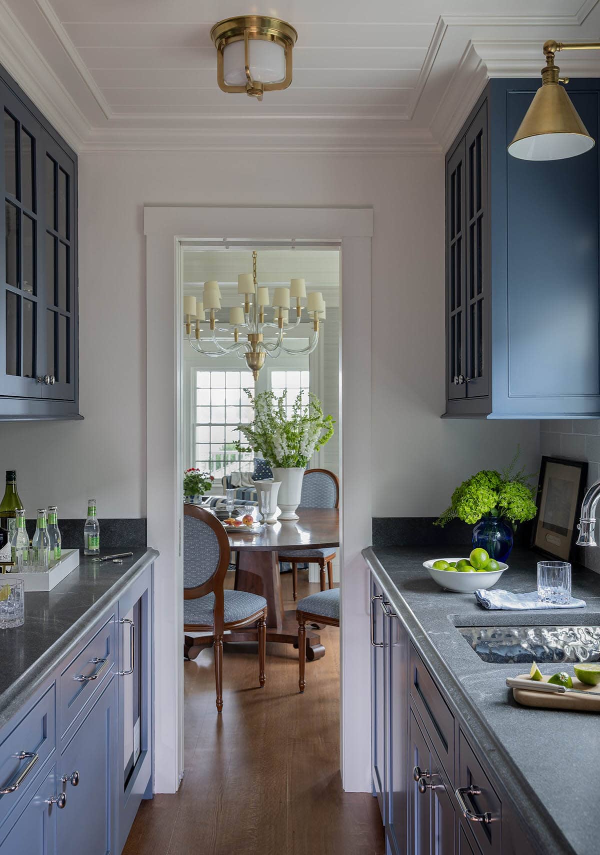 Navy butler's pantry with dark granite countertops leading to formal dining room