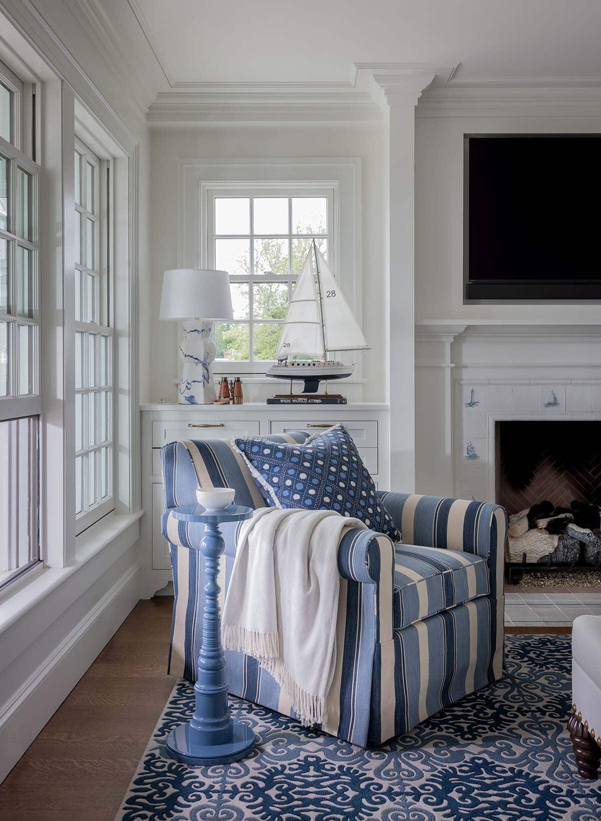 Blue and white striped armchair beside fireplace with nautical tile surround