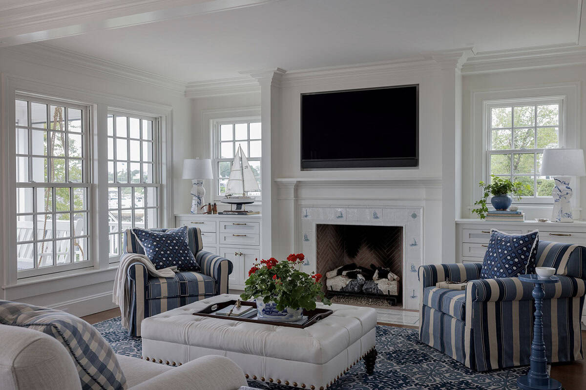 Coastal living room with blue striped armchairs, tufted ottoman and sailboat fireplace tiles