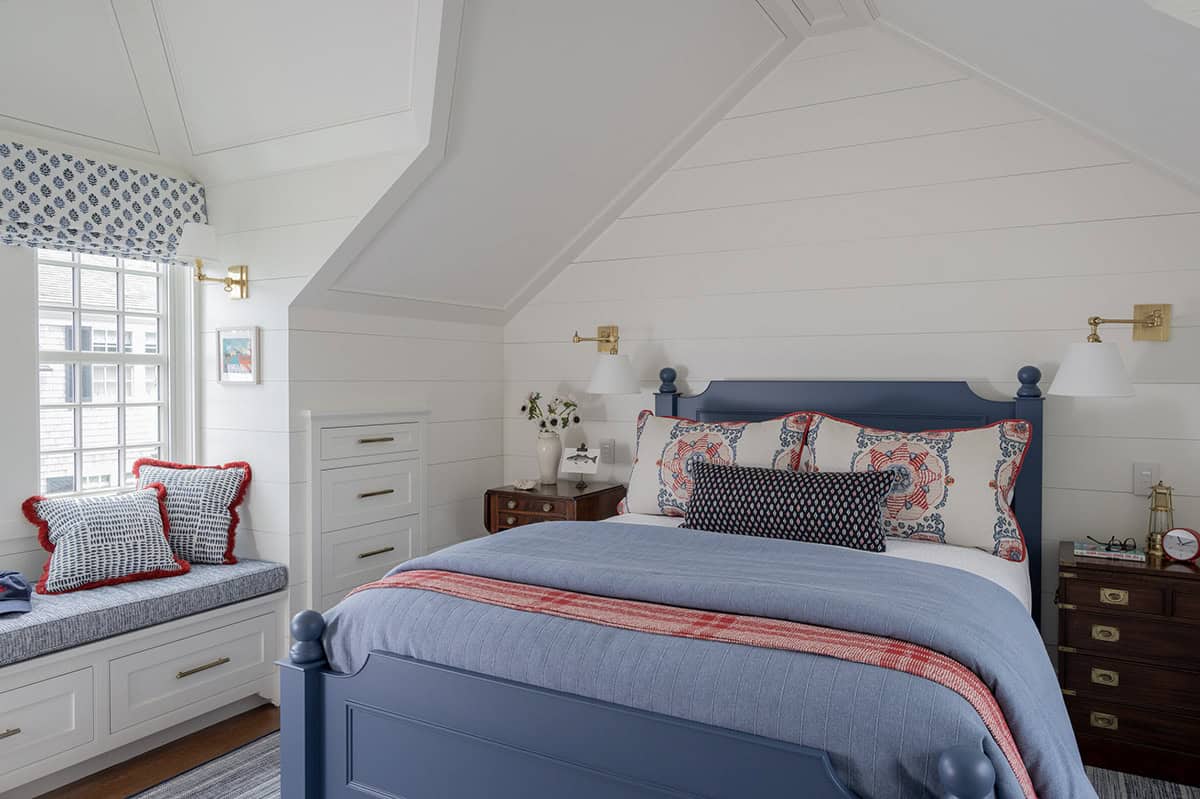 Attic bedroom with navy painted bed, shiplap walls, vaulted ceiling and window seat