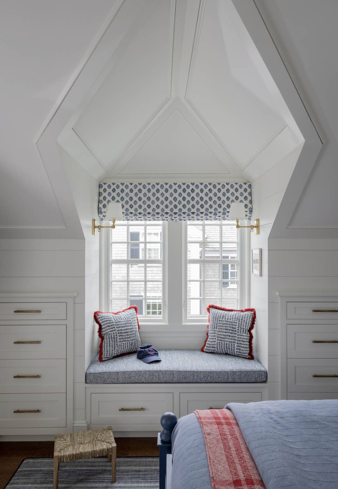Attic bedroom window nook with built-in storage drawers and navy block print roman shade