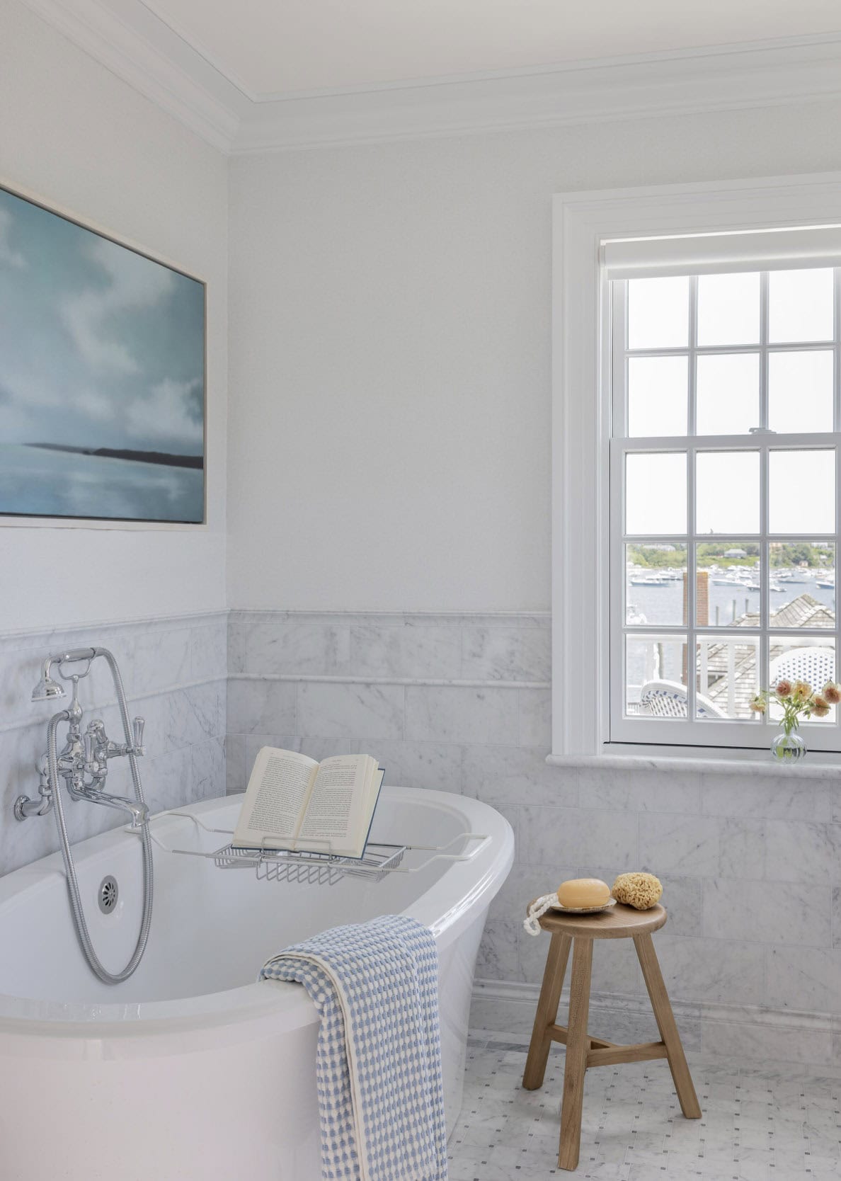 Freestanding soaking tub with marble surround, chrome fixtures and harbor view window