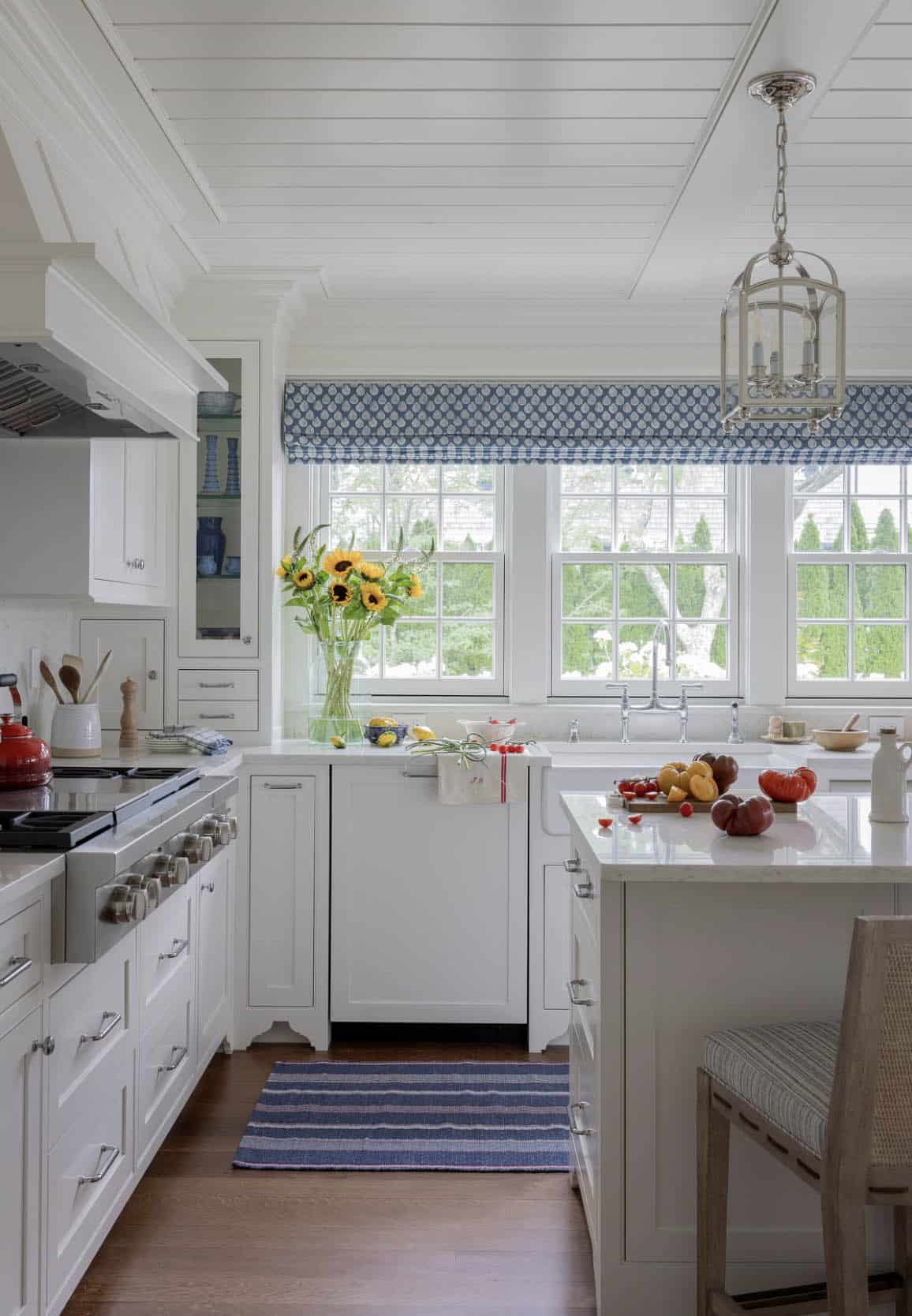 White kitchen with shiplap ceiling, blue roman shades, lantern pendant and farmhouse sink