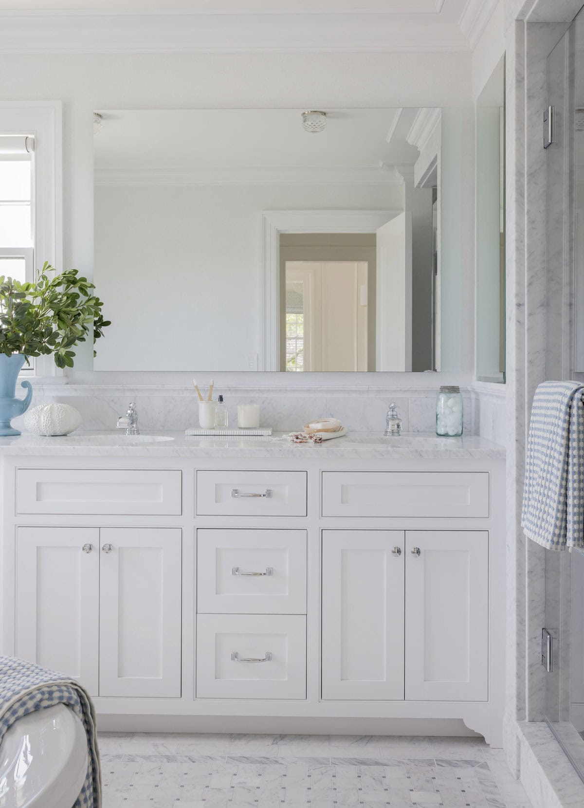 Primary bathroom with white double vanity, Carrara marble countertop and chrome fixtures