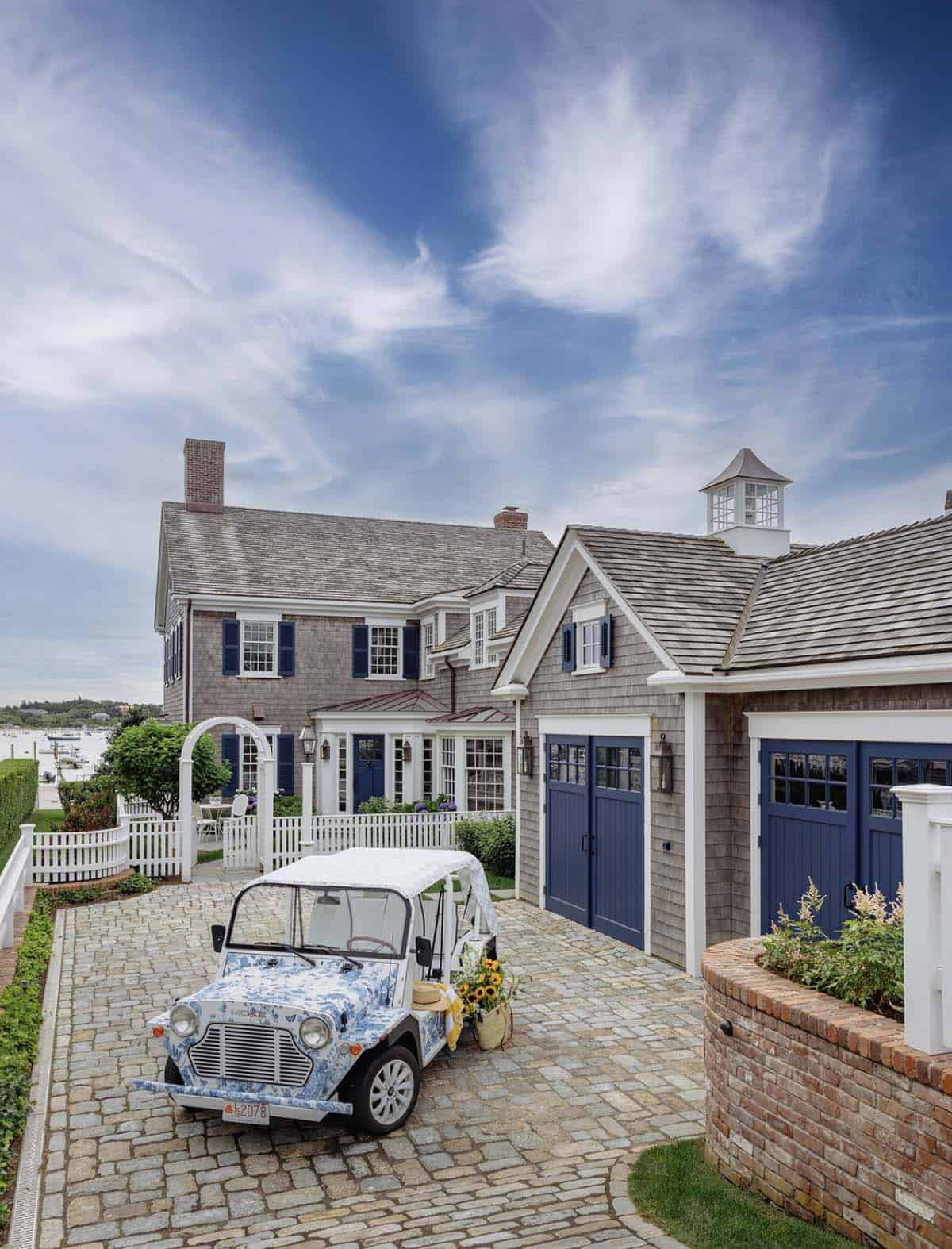 Decorated golf cart parked in cobblestone driveway of shingle-style coastal home