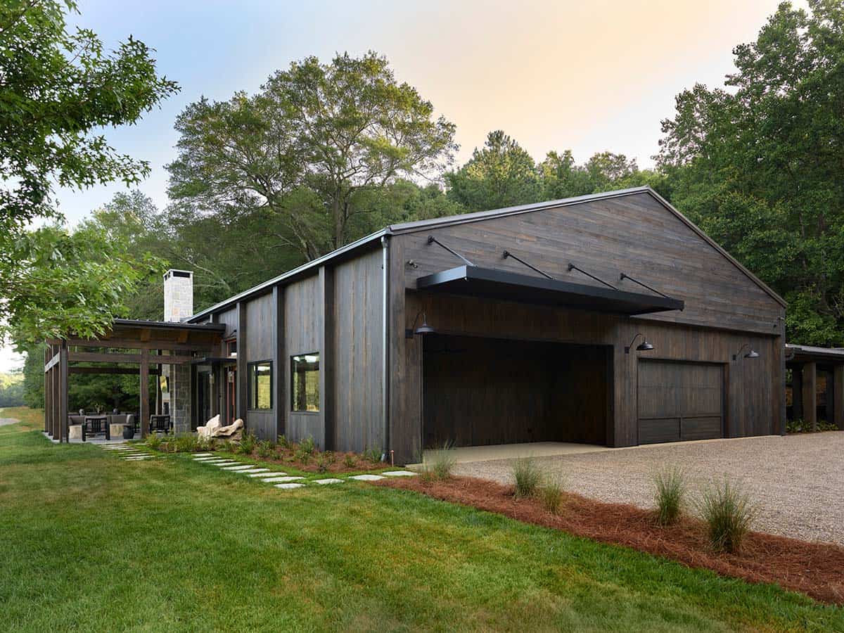 Contemporary barn-style home with weathered wood siding, metal roof, black barn lights, and covered pergola in Georgia