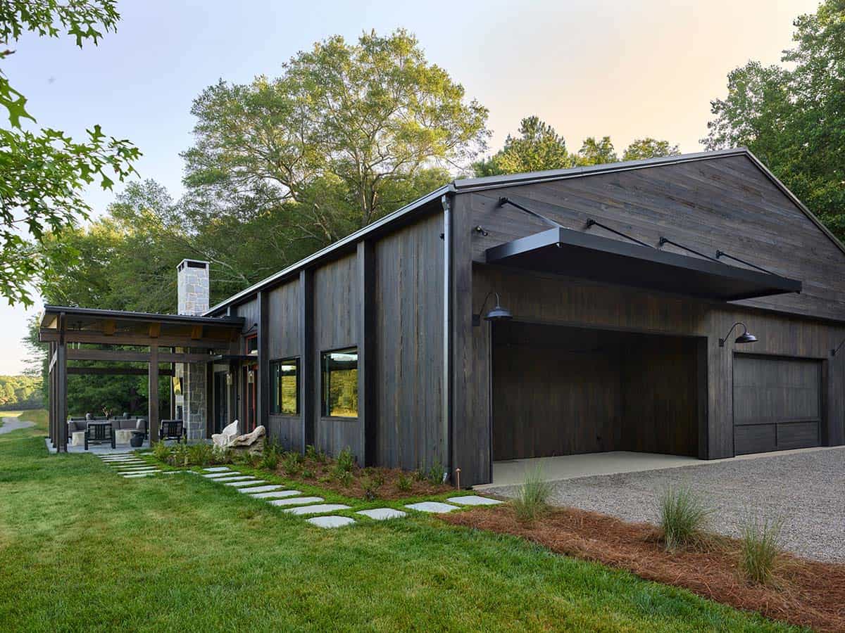 Side view of weathered wood contemporary home with open garage, black canopy awning, and flagstone path