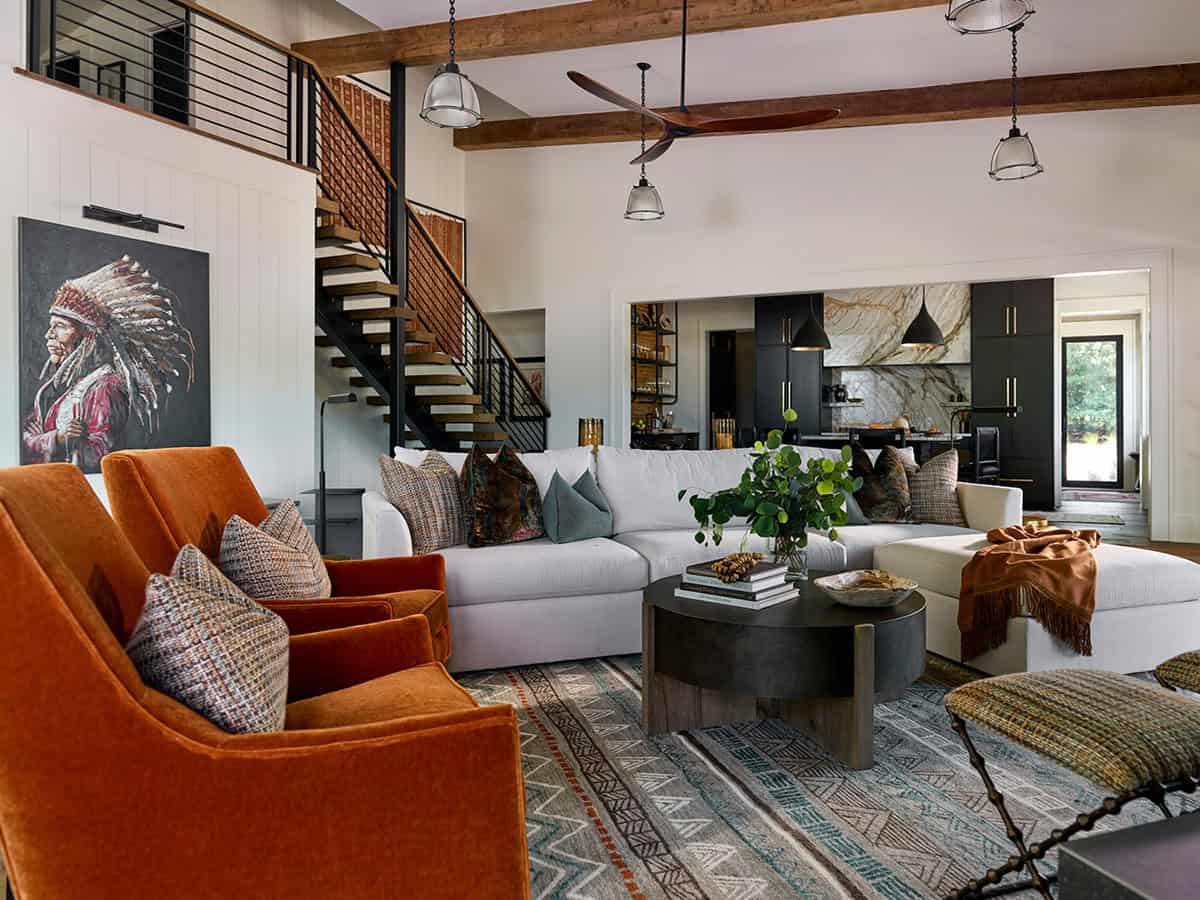 Open-plan living room with orange velvet armchairs, sectional sofa, and exposed wood beam ceiling