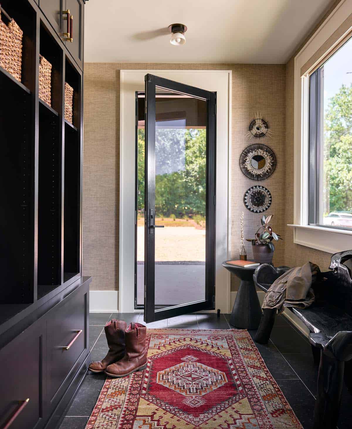 Mudroom entryway with dark built-in storage, red kilim runner, and glass pivot door