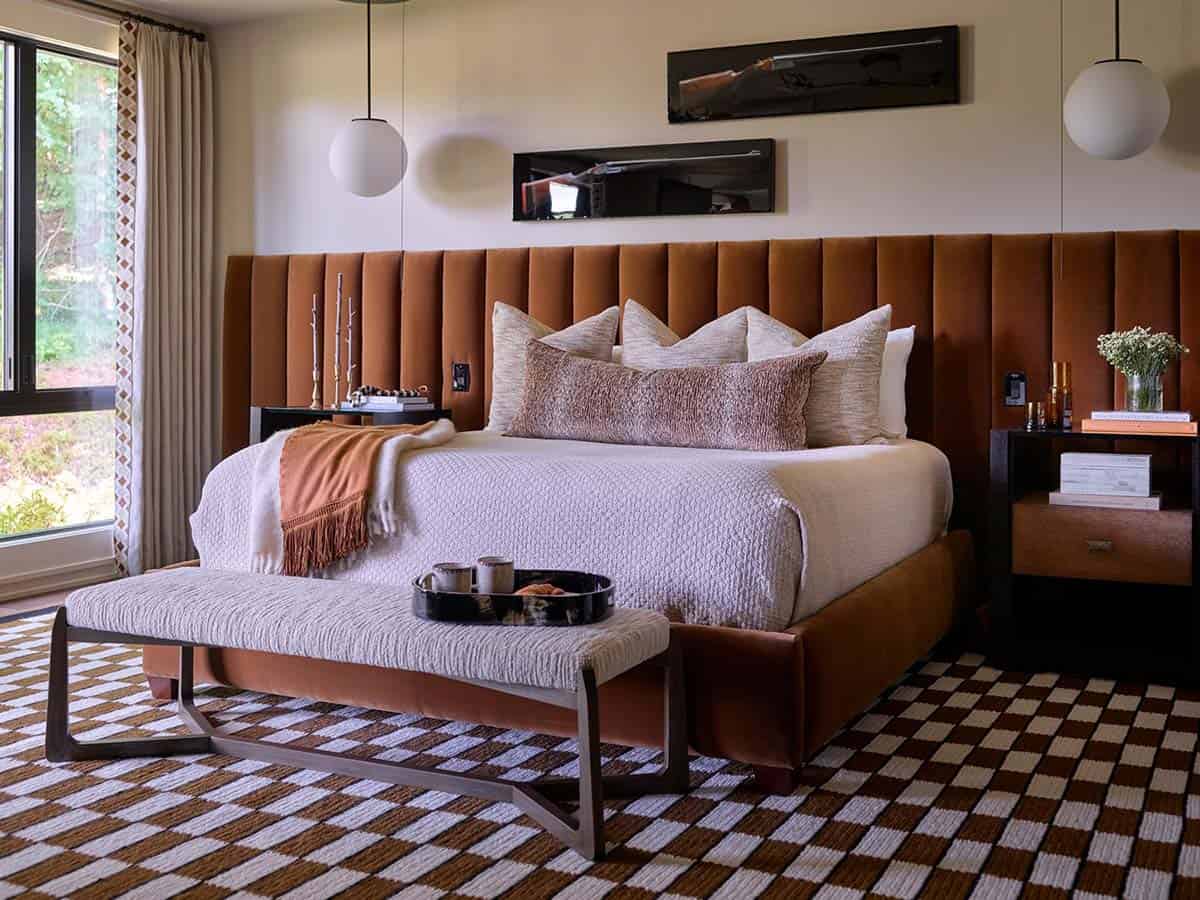 Primary bedroom with tall burnt-orange channel-tufted headboard and checkered wool rug