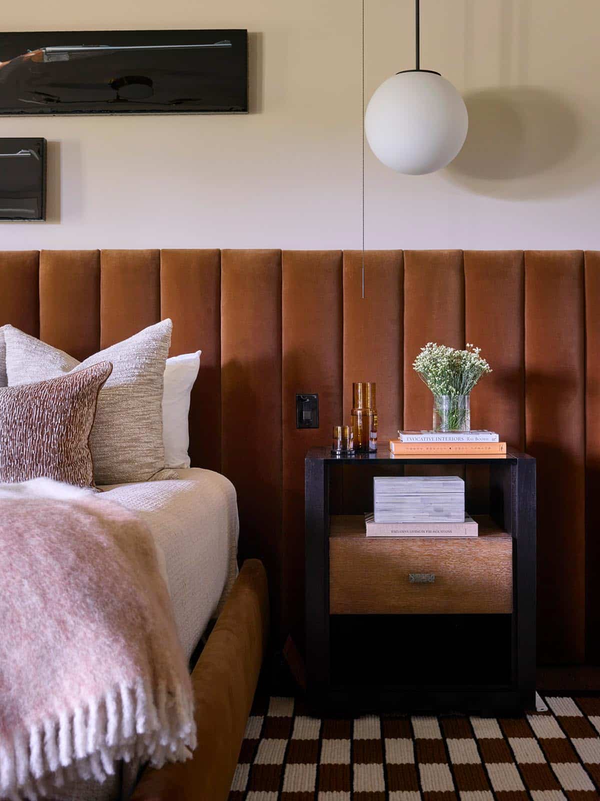 Close-up of dark wood nightstand against channel-tufted orange velvet headboard wall