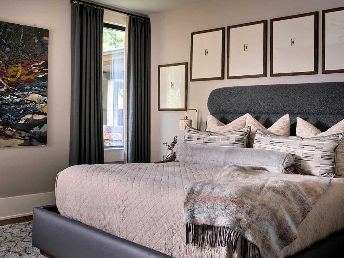 Guest bedroom with charcoal boucle headboard, gallery wall, and colorful abstract painting
