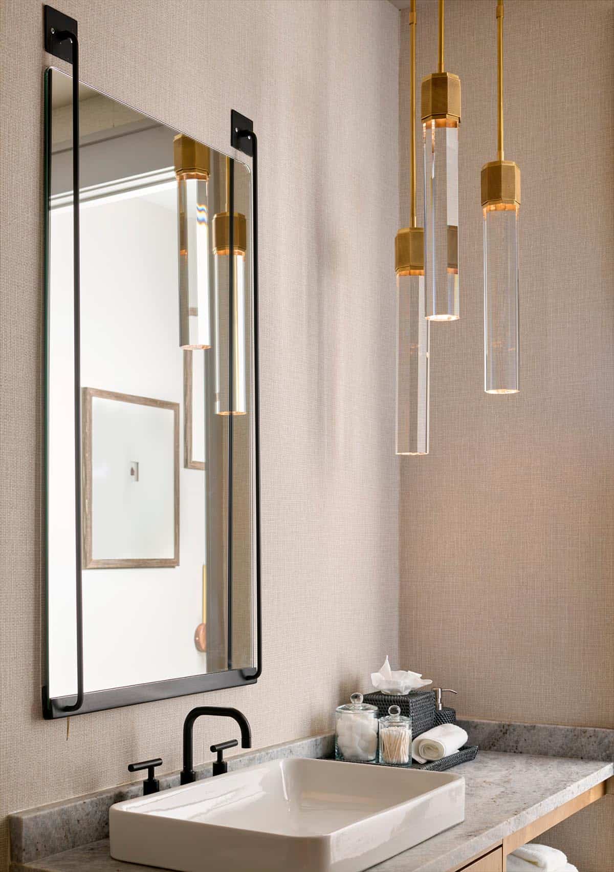 Guest bathroom with black-framed mirror and cluster of brass and glass cylinder pendant lights
