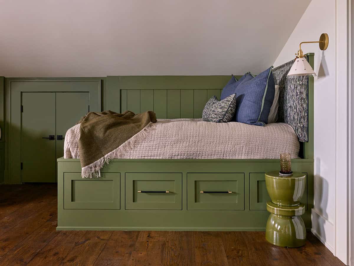 Green painted built-in bed with under-drawer storage and brass wall sconce