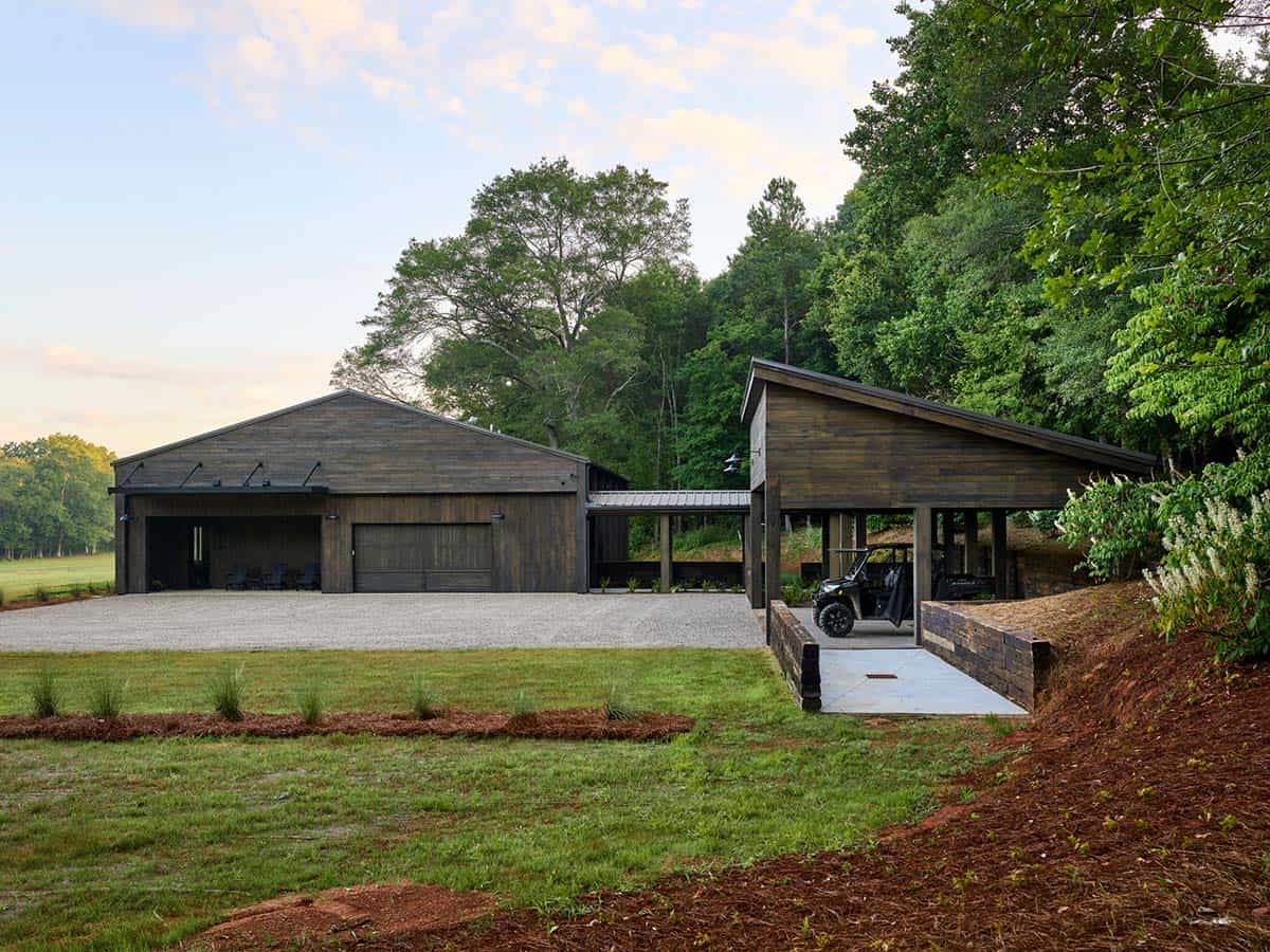 Weathered wood barn and open carport structure at dusk surrounded by green meadow