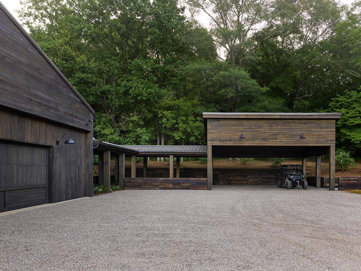 Rear view of weathered wood barn and open equipment shelter with gravel courtyard