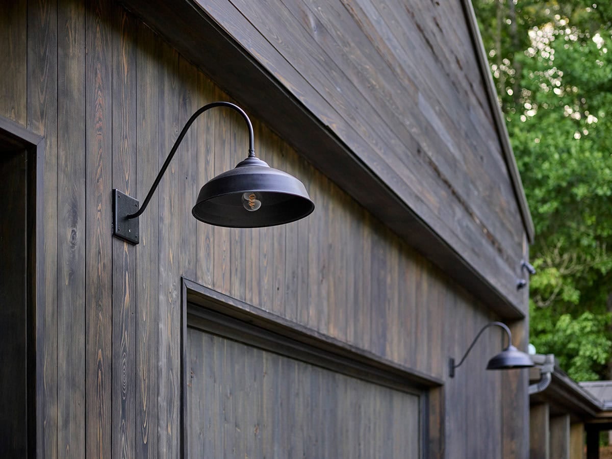 Black gooseneck barn light mounted on weathered vertical wood siding