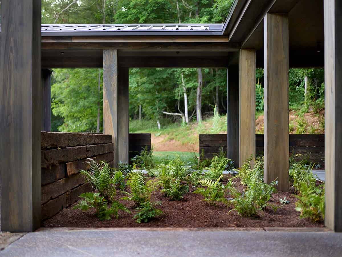 Covered breezeway with wood columns, railroad tie retaining walls, and fern garden beds