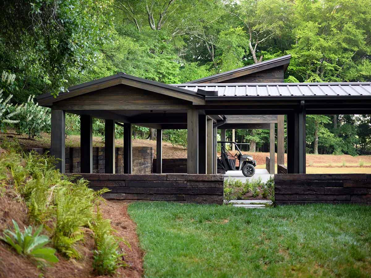 Open wood carport with angled metal roof, railroad tie walls, and UTV parked inside