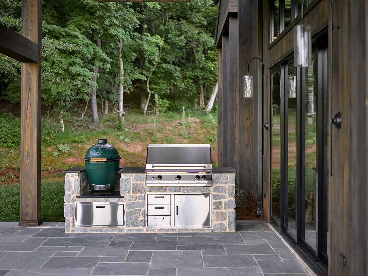 Outdoor kitchen with Big Green Egg, stainless grill, and stone base on slate patio
