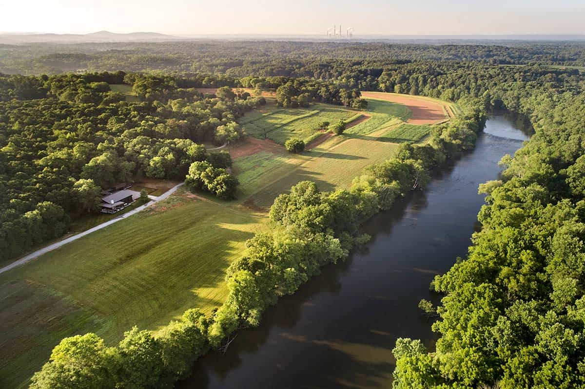 Aerial view of contemporary home tucked into wooded riverfront property