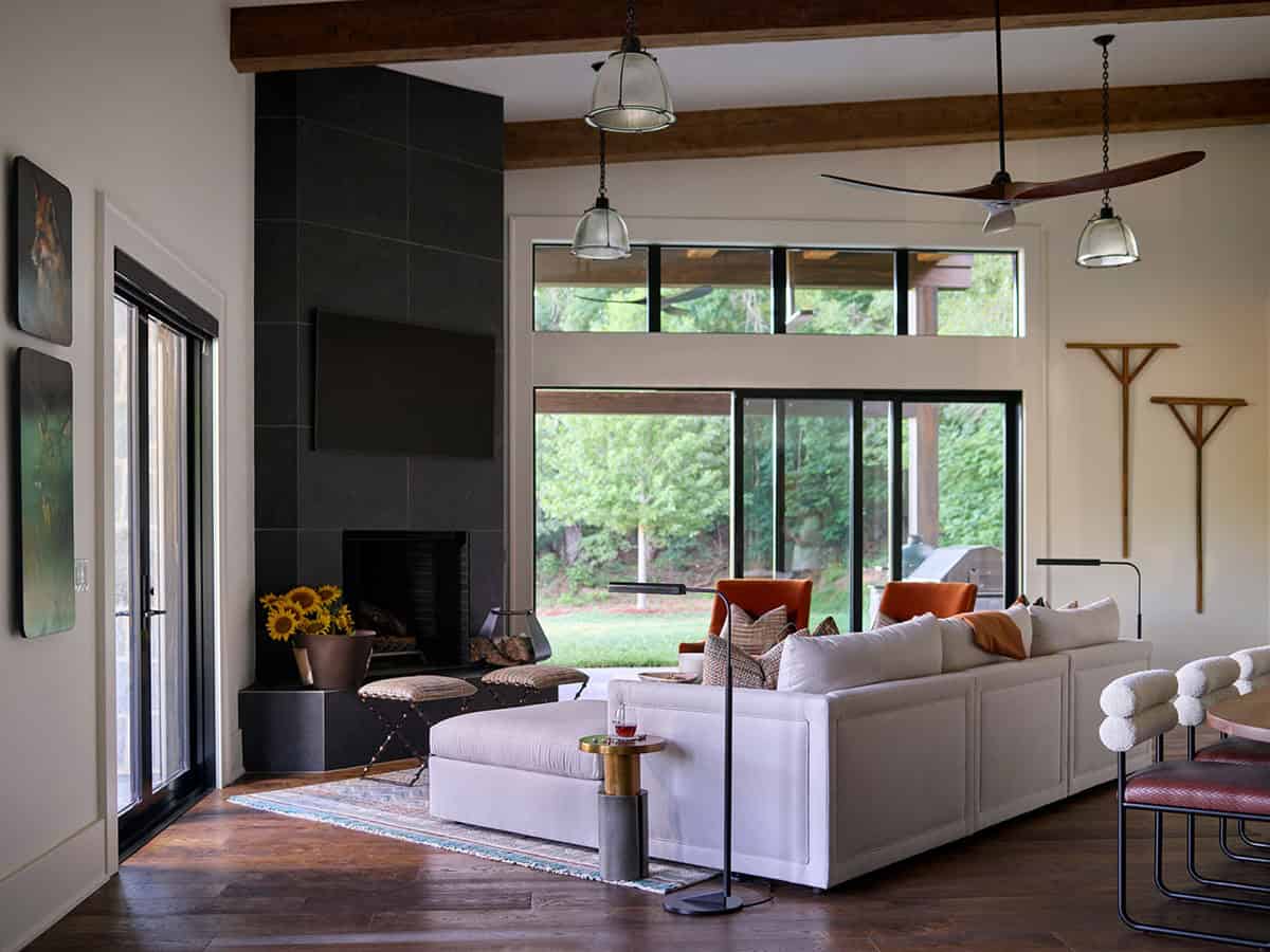 Living room with black slate fireplace, white sectional, exposed beams, and large sliding doors