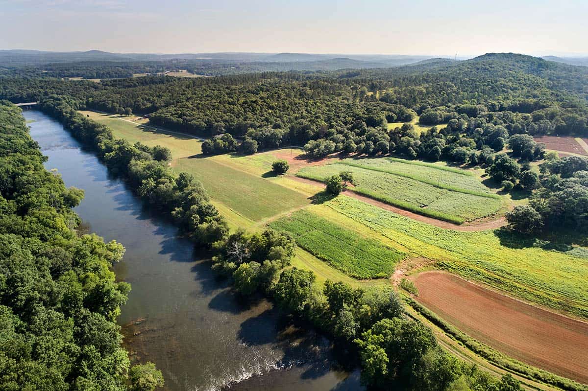 Aerial view of contemporary home tucked into wooded riverfront property